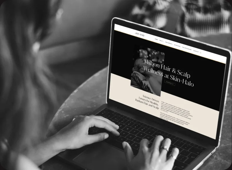 Hands on laptop showing Skin + Halo wellness site